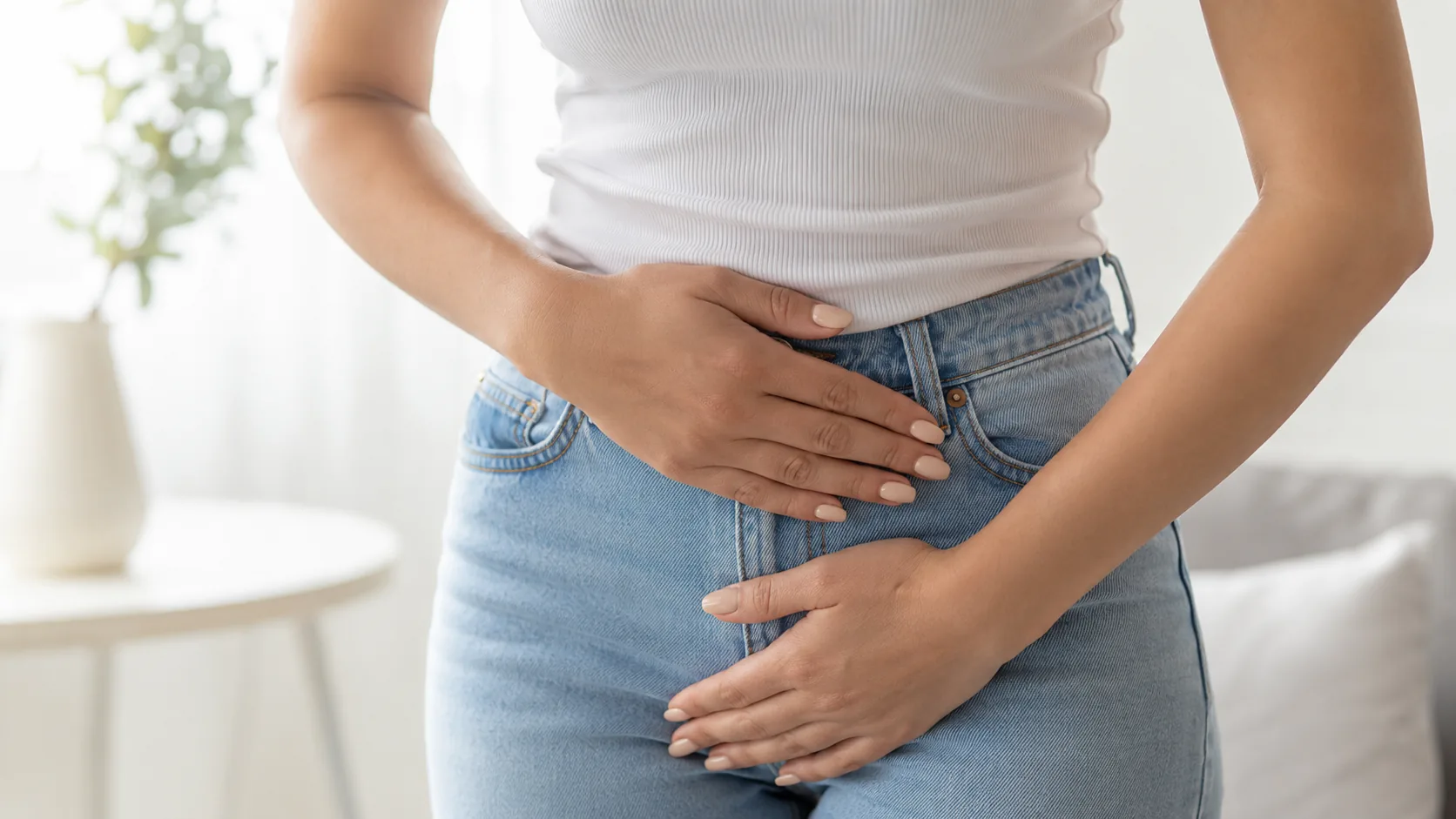 Woman holding her lower abdomen and pelvic area, representing incontinence symptoms