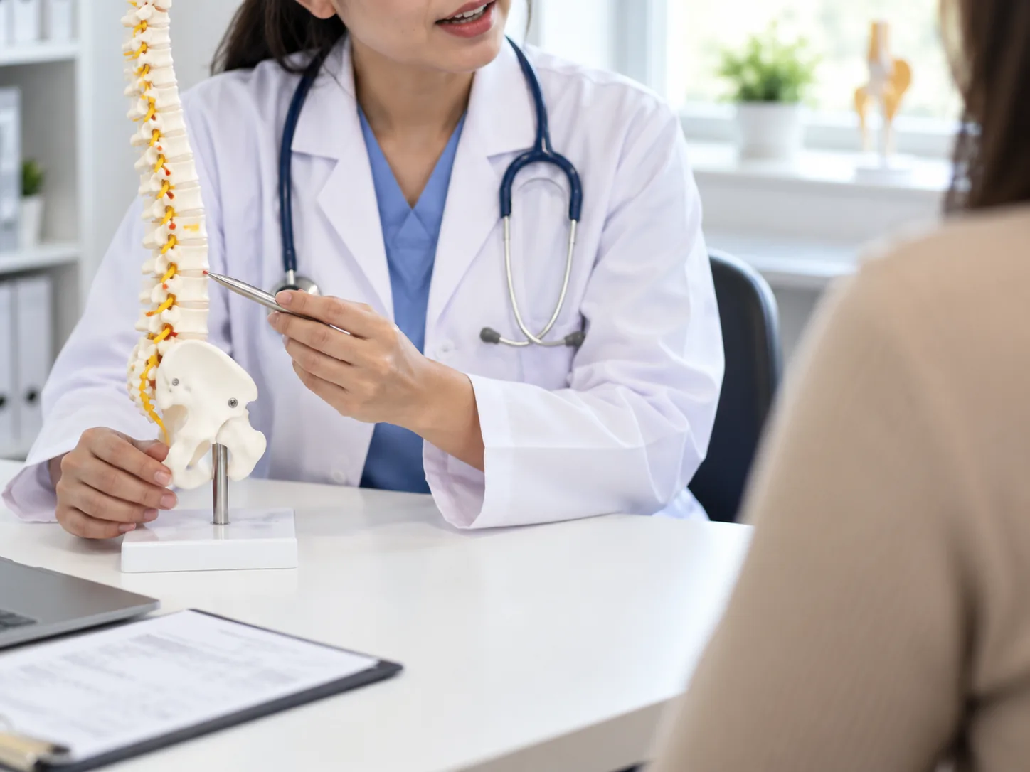 Doctor explaining a spine model to a patient during a spinal consultation