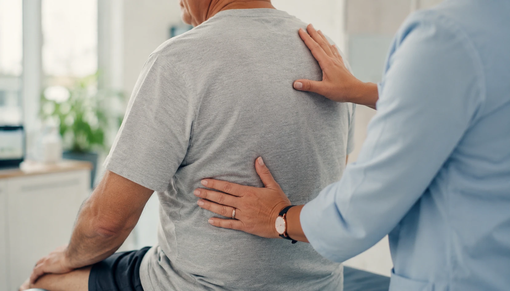 Healthcare professional examining a patient’s back during a back pain treatment or physical therapy session.