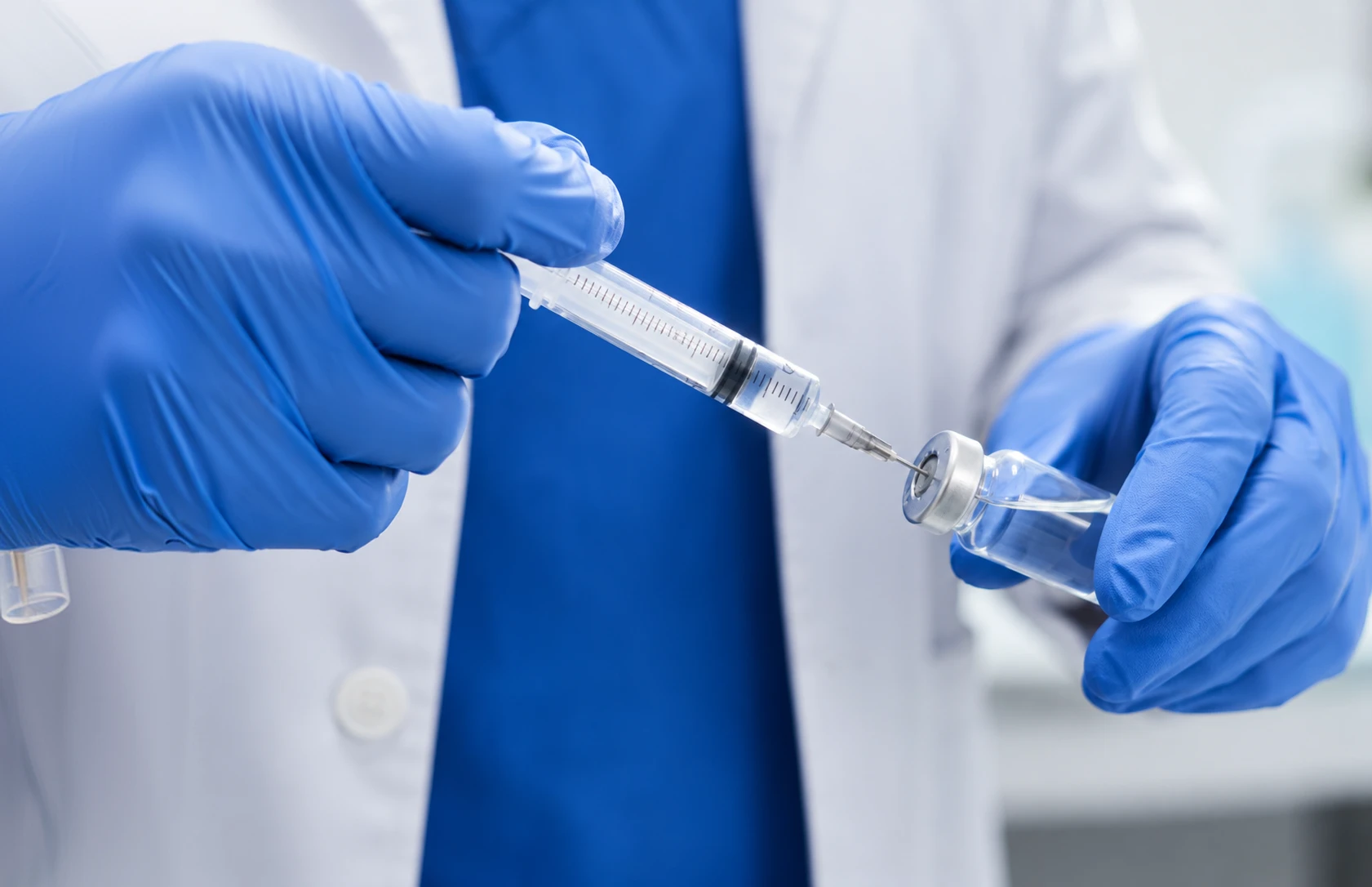 Healthcare professional preparing a syringe and vial, representing minimally invasive treatments for back pain or spinal injection care.